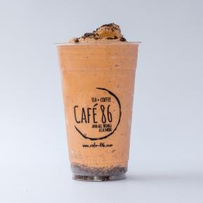 Café 86 blended orange drink in a clear cup topped with chocolate cookie pieces.